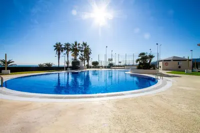 a large blue swimming pool with palm trees in the background at ESPACIO 15 - Primera Línea de Playa in Cullera