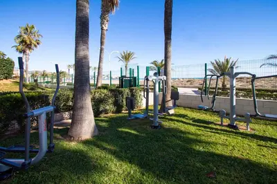 a park with a bunch of swings and palm trees at ESPACIO 15 - Primera Línea de Playa in Cullera