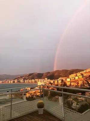 a rainbow in the sky over a city with a balcony at Racó de la Mar in Faro de Cullera