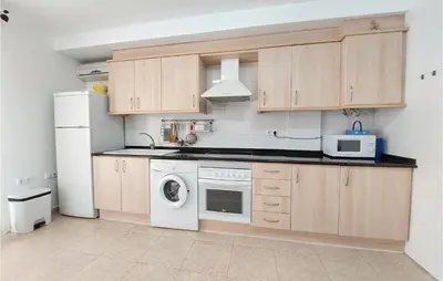 a kitchen with wooden cabinets and a white appliance at Gorgeous Apartment In Playa De Moncofa in Moncófar