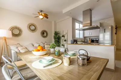 a kitchen and dining room with a wooden table with a bowl of fruit at Gran Vía by District Key in Valencia