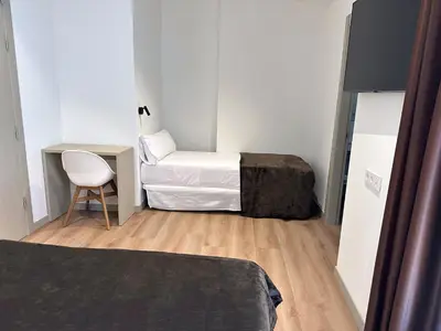 a small room with two beds and a chair at Hotel BESTPRICE Valencia in Valencia