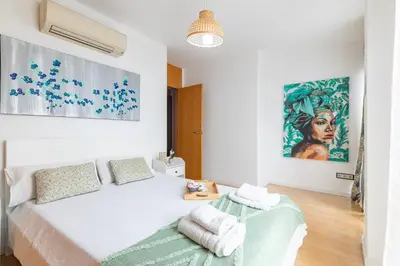 a white bedroom with a bed and a painting on the wall at Grand Villa Valencia - 8 min to Center by Metro in Valencia