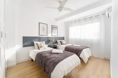 two beds in a bedroom with white walls and wood floors at Espectacular piso reformado al lado del rio Turia in Valencia