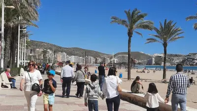 a group of people walking on the beach at Terraza con vistas al mar Parking privado 120 mts, junto a la playa in Cullera
