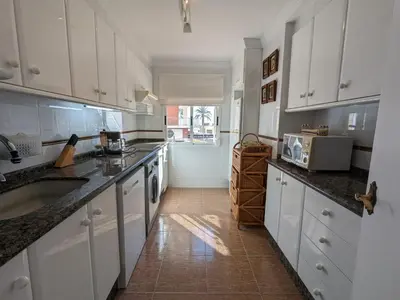 a large kitchen with white cabinets and a sink at Terraza con vistas al mar Parking privado 120 mts, junto a la playa in Cullera