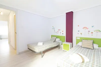 a room with two beds and a wall with flowers on it at Global Vacacional, Apartamento de 4 habitaciones a 100 m de la playa in Puerto de Sagunto