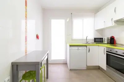 a kitchen with white cabinets and a table in it at Global Vacacional, Apartamento de 4 habitaciones a 100 m de la playa in Puerto de Sagunto