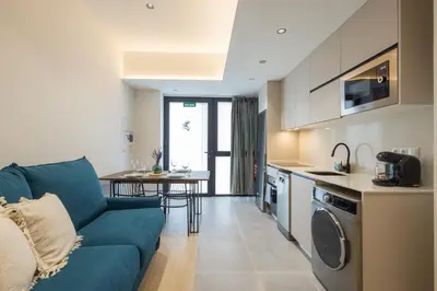 a living room with a blue couch and a kitchen at FLORIT FLATS - The Green Apartments in Valencia