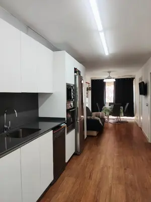 a kitchen with white cabinets and a living room at Playa Puebla de Farnals Valencia in Masalfasar